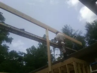 Carpenter setting a ridge beam over a new addition frame — Ice Dam Removal by Roofing Brothers in Bell