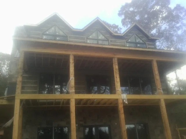 Dormers and porch framing on a large log home under construction — Roof Coating work by our crew in Bell
